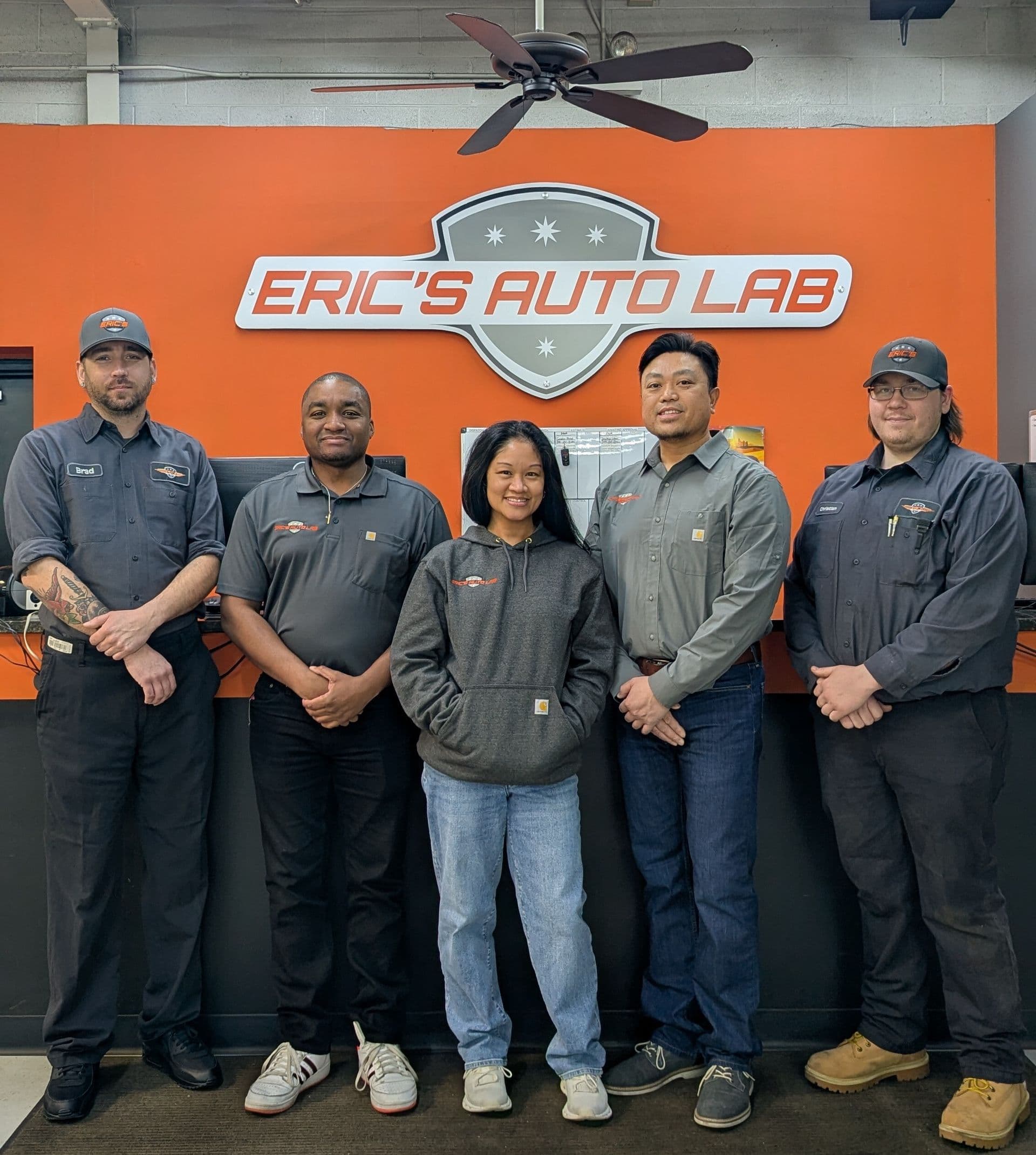 The Eric's Auto Lab team standing together in front of the shop sign